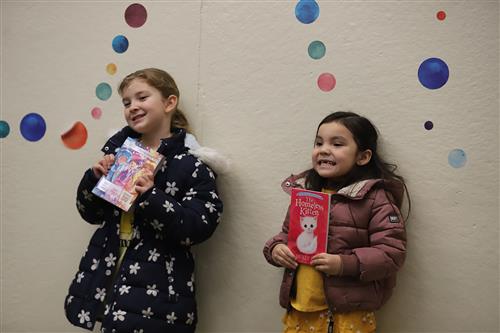 Students holding books and smiling.